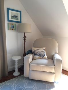 a living room with a chair, lamp and pictures on the wall