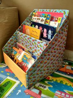 a toy storage box filled with books on top of a colorful carpeted floor next to a wall