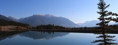 a lake surrounded by mountains with trees in the foreground