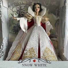 a snow white doll in a box with gold trimmings and red caper