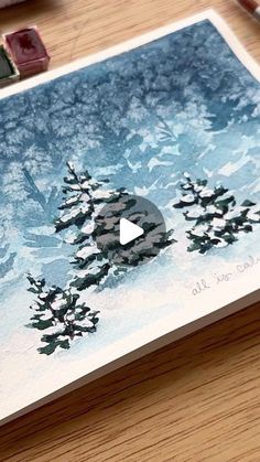 a christmas card with an image of trees in the snow and a video playing on it