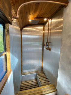 the inside of a small bathroom with wood flooring and metal walls, along with wooden slats