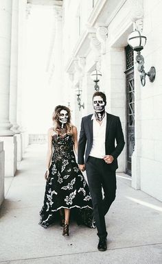 a man and woman in skeleton makeup walking down the street