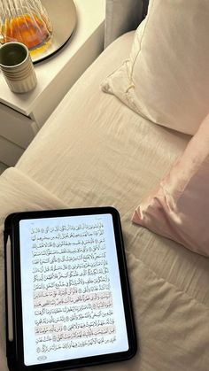 a tablet sitting on top of a bed next to pillows