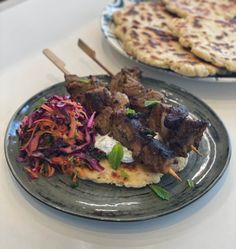 two plates with food on them sitting on a table next to some pita bread