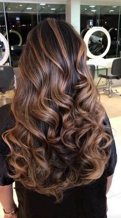 the back of a woman's head with long, wavy hair in a salon