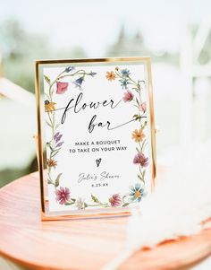 a flower bar sign sitting on top of a wooden table