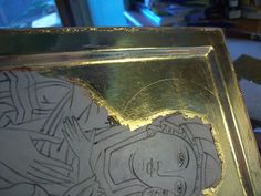 a gold plate with a drawing of a woman on it's side, in front of a window