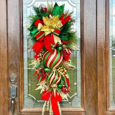 a christmas wreath on the front door of a house with red, green and gold decorations