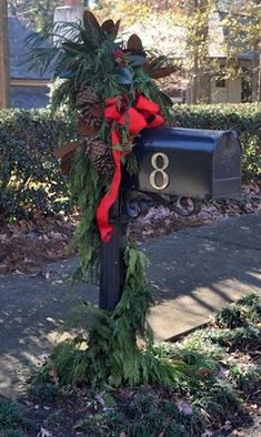 a mailbox decorated with greenery and red ribbon