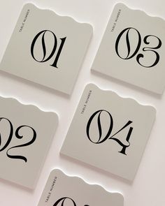 four black and white numbered numbers are shown on a table top with one number in the middle