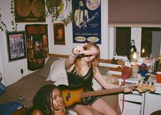 two women sitting on a bed with guitars in their hands and one woman holding a guitar