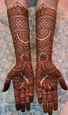 the hands and feet of a woman with henna tattoos on their arms, both showing intricate