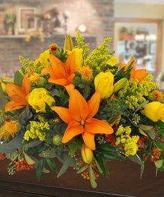 an arrangement of orange and yellow flowers on a table