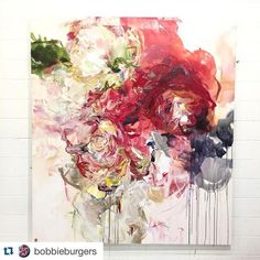 an abstract painting with red, pink and white flowers on it's side hanging on a brick wall