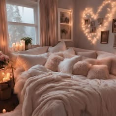 a bed with pillows and blankets in front of a window filled with lit up candles