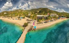 an aerial view of a beach resort with blue water and palm trees in the background