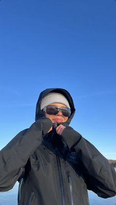 a man standing in the snow holding his jacket over his face