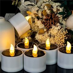 tea light candles sitting on top of a table next to flowers and a white vase