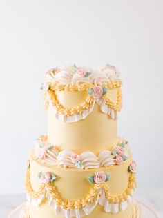 a three tiered cake with flowers on it's sides and the top layer is yellow