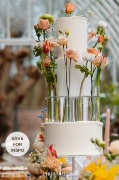 a three tiered white wedding cake with flowers on top