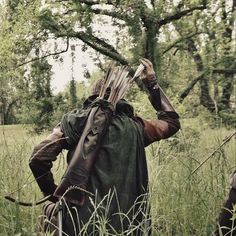 two people in the woods with arrows on their heads and one holding an arrow over his head