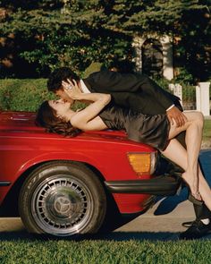 a man and woman kissing in the back of a red car