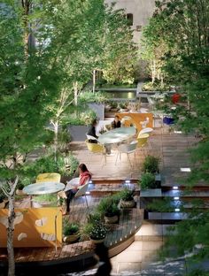 people are sitting at tables in the middle of an outdoor area with lots of trees