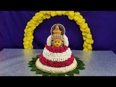 there is a cake decorated with flowers and a doll on it's head in front of a purple backdrop