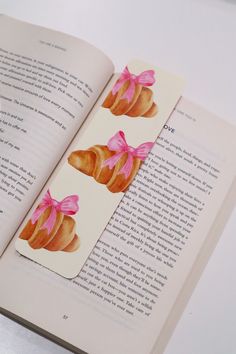 an open book with pink bows on it and some breads in the pages next to it