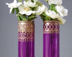 two purple vases with white flowers in them