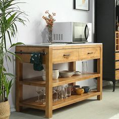 a kitchen island with wine glasses on it in front of a potted plant and microwave