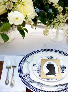 the table is set with plates, silverware and flowers