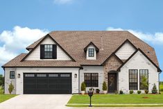 a white house with black garage doors and windows