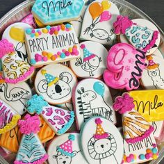 decorated cookies in the shape of animals and letters on a platter with name tags