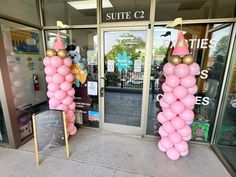 two pink and gold balloons are in front of a building with a sign that says suite c