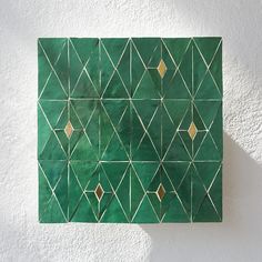 a piece of art that looks like it has been made out of green tiles with gold geometric designs