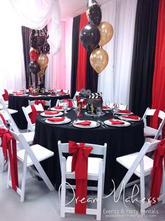 a black table topped with white chairs and red ribbon tied around the tables in front of balloons