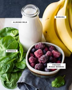 a bowl of raspberries next to bananas and spinach on a cloth with labels