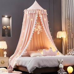 a canopy bed is decorated with pink and white lights for a girls's bedroom