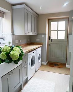 a washer and dryer sitting in a kitchen next to a doorway with flowers on the counter