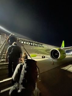 several people are walking towards an airplane on the tarmac at night, with stairs leading up to it