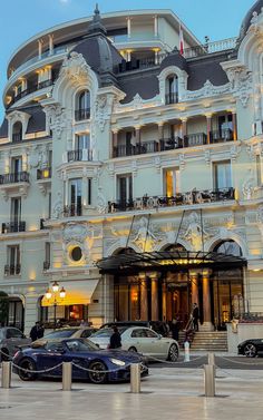 cars parked in front of a large white building with balconies on the top