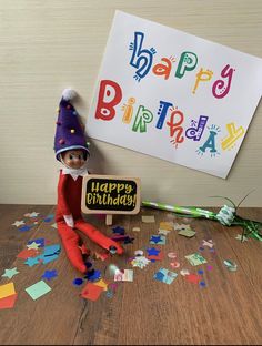 an elf with a birthday sign and confetti on the floor