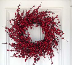 a white door with a red berry wreath on it