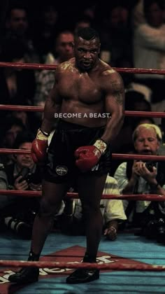 a man standing next to a boxing ring with his hands on his hips and other people sitting in the stands watching