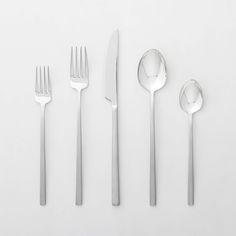 four forks, two spoons and one knife on a white surface