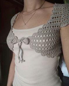 a woman wearing a white top with a crochet design on the chest and shoulder