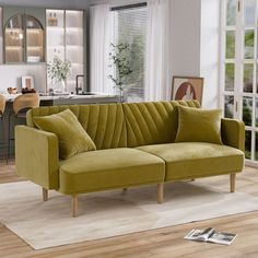 a green couch sitting on top of a hard wood floor next to a white rug