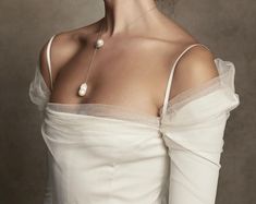 a woman wearing a white dress and pearl necklace